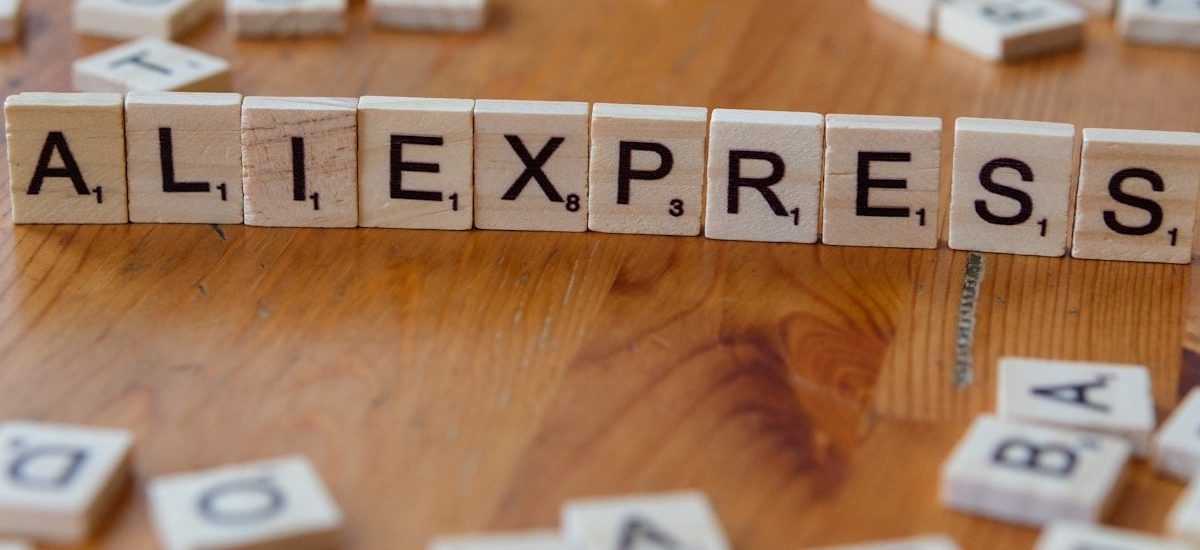 A wooden block spelling the word allexpress on a table