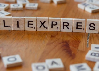 A wooden block spelling the word allexpress on a table