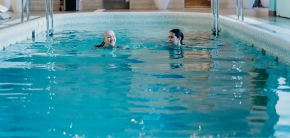Senior woman and adult woman enjoying a relaxing swim in an indoor pool, featuring leisure and relaxation.